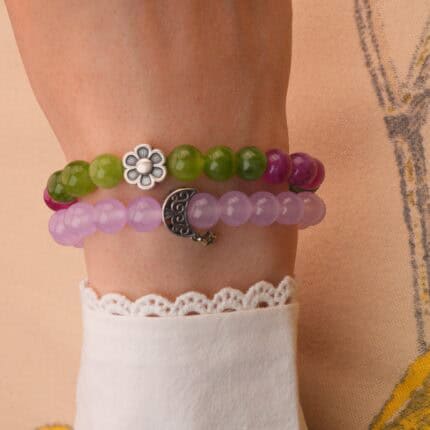 Model wearing stacked amethyst and tourmaline bracelets on wrist.