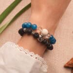 Model wearing stacked lava and gemstone bracelets.