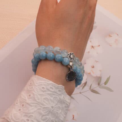 Model wearing blue chalcedony and aquamarine bracelets stacked together.
