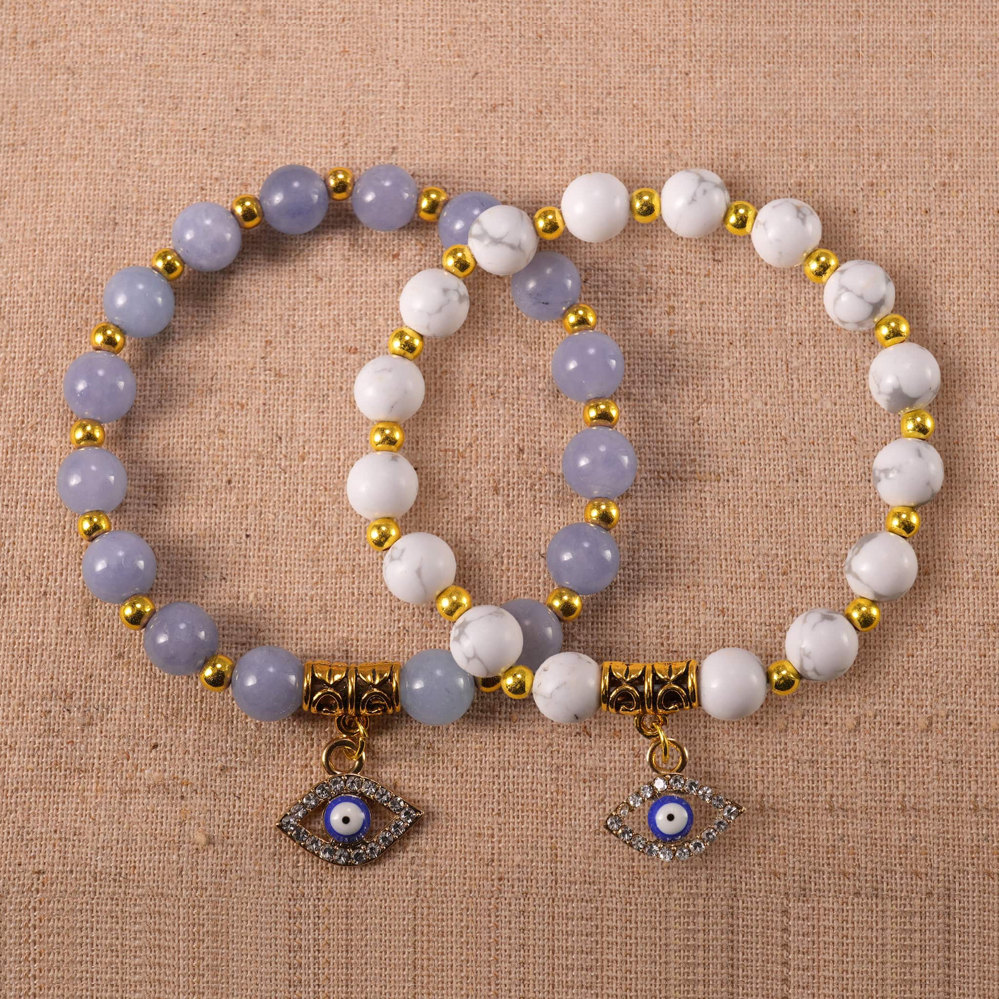 Main image of stacked evil eye bracelets in blue and white tones.