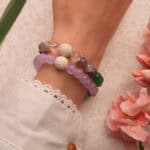 Model wearing layered lava stone bracelets with blue and purple gems.