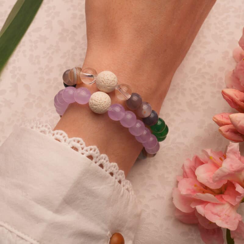 Model wearing layered lava stone bracelets with blue and purple gems.