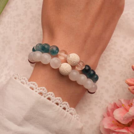 Model wearing layered gemstone and lava bracelets.