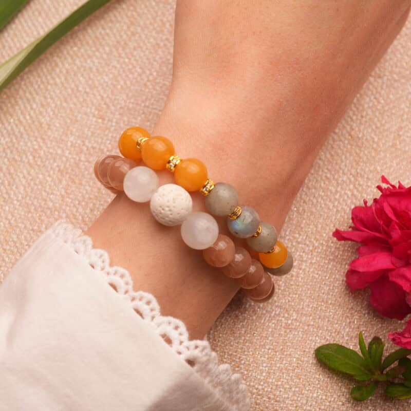 Model wearing layered gemstone and lava bracelets.