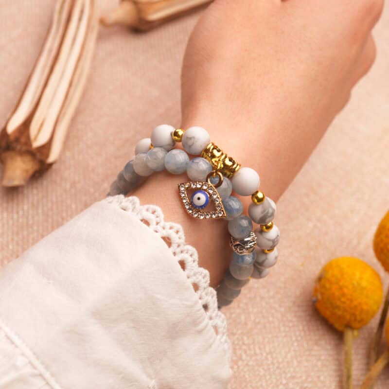 Model wearing gemstone stack in vibrant blue, red, and white tones.