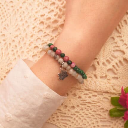 Model wearing stacked malachite and amazonite gemstone bracelets.