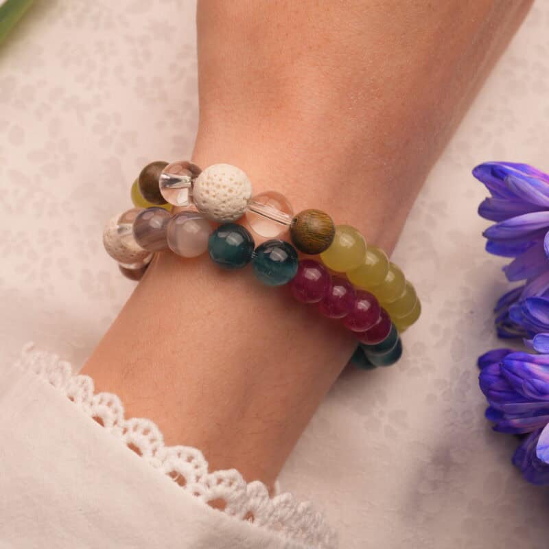 Model wearing stacked bracelets in light and dark tones.