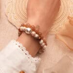 Model wearing peach moonstone and Shoushan stone bracelet stack.