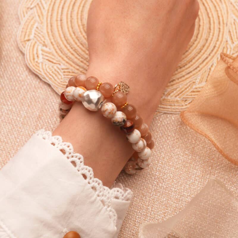 Model wearing peach moonstone and Shoushan stone bracelet stack.