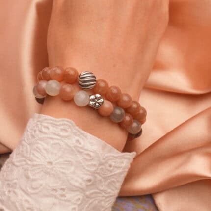 Model wearing stacked peach moonstone and white agate S925 bracelets.