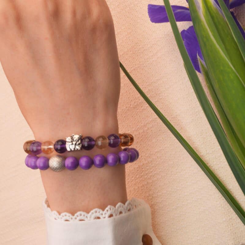 Model wearing stacked phosphosiderite and ametrine crystal bracelets on wrist.