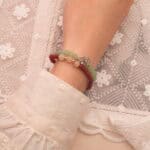 Model wearing stacked gemstone bracelets in warm and cool tones.