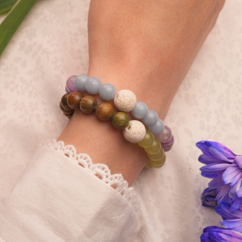 Model wearing stacked bracelets with warm and cool tones.