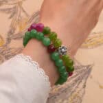 Model wearing stacked tourmaline and aventurine-red agate bracelets on wrist.