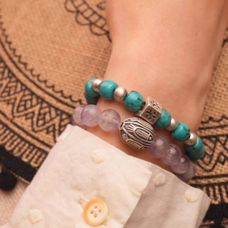 Model wearing bright and soft gemstone bracelets in a layered look.