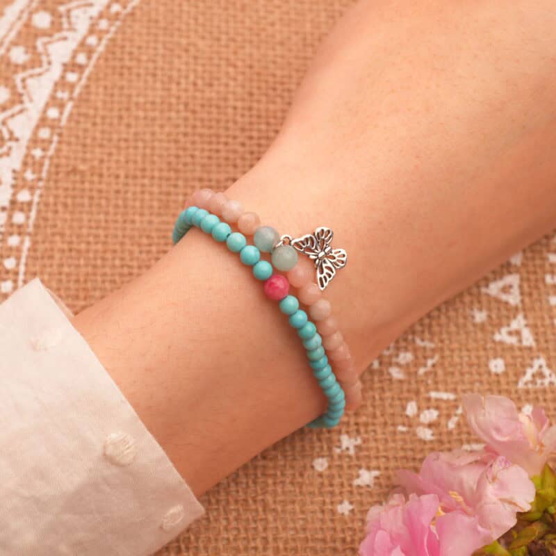 Model wearing colorful gemstone bracelet stack.