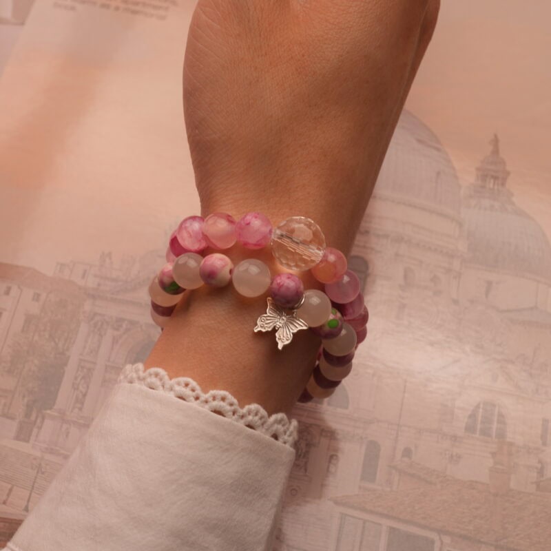 Model wearing two pastel-toned stacked bracelets on wrist.