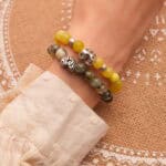 Model wearing stacked gemstone bracelets in soft natural tones.