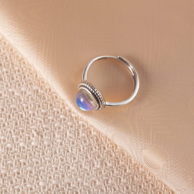 Adjustable moonstone ring displayed on white background, showcasing its glowing, iridescent surface.