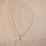 A close-up, centered shot of an adjustable natural pearl necklace on a neutral background, highlighting its full shape and lustrous pearls.