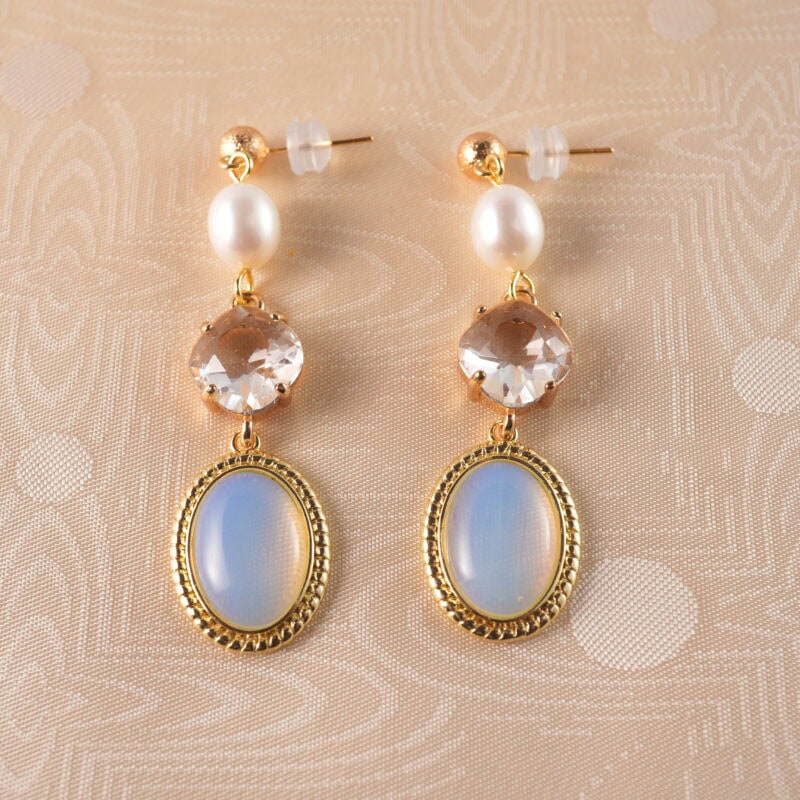 A pair of elegant opal and pearl drop earrings with a soft glow, set against a clean, minimal background.