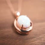 An opal pendant resting on a decorative surface under natural light, showcasing its dreamy iridescent glow.