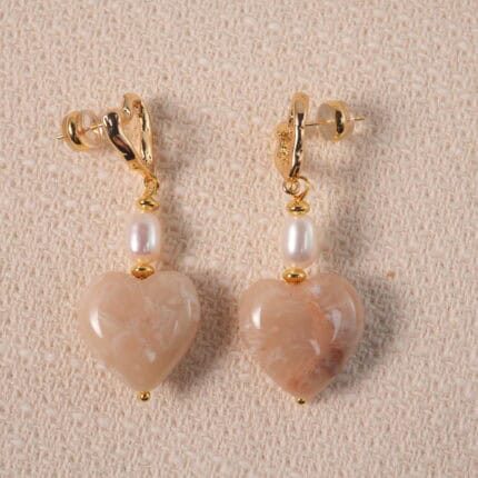 A pair of heart-shaped pearl drop earrings displayed on a white background, showcasing elegant and romantic design.