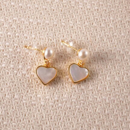 A pair of heart-shaped drop earrings with pearls, featuring a romantic design and clean background.
