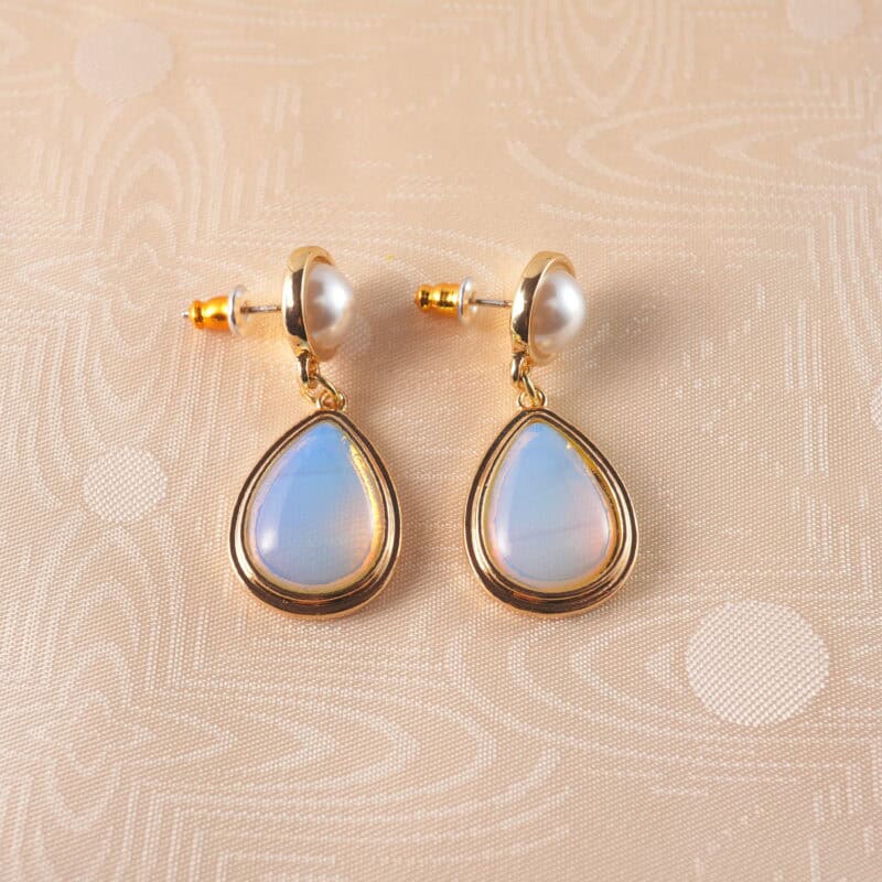 A pair of pearl and opal teardrop earrings with a delicate design, set against a clean, fresh background.
