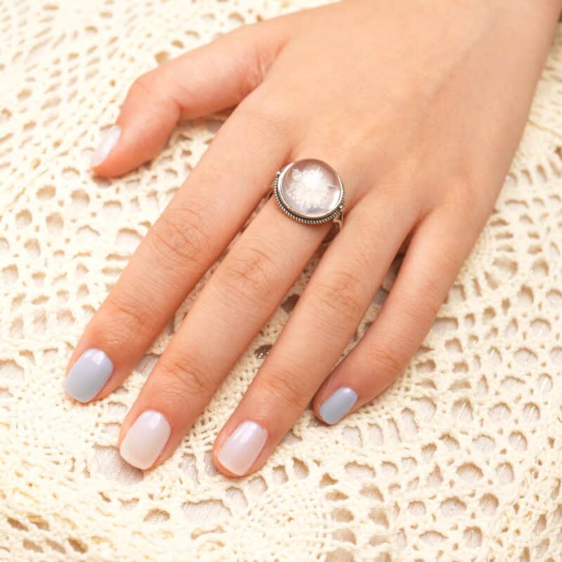 Snowflake-carved quartz ring worn on the hand, adding a delicate, frosty charm.