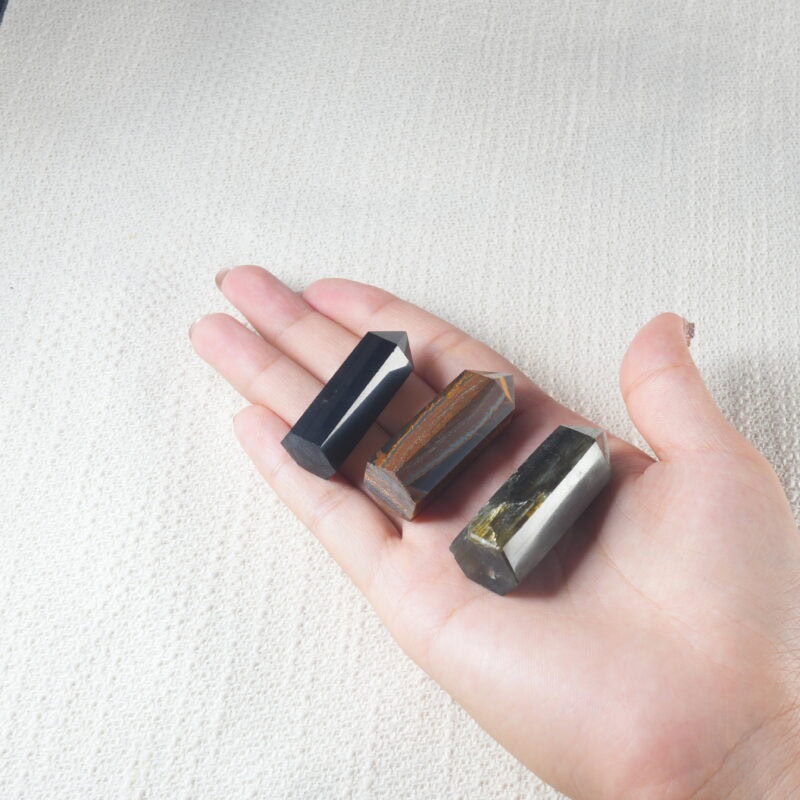 Hand holding polished obsidian crystal point tower for spiritual grounding