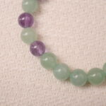 Close-up of the Prehnite and Amethyst bracelet, highlighting the smooth texture and shine of the prehnite and amethyst beads with the silver spacer in between.