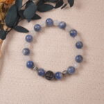 The blue Kyanite and white Moonstone bracelet displayed on a soft fabric background, surrounded by natural elements. The bracelet’s calming colors and design make it a perfect accessory for peaceful and serene moments.