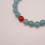 Close-up of the Green Aventurine and Red Agate beads, showcasing their smooth texture and harmonious color combination, with a central white bead adding elegance.