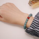 A model wearing the Green Aventurine and Red Agate bracelet on their wrist. The soothing green and vibrant red colors create a balanced, peaceful, and energetic look.