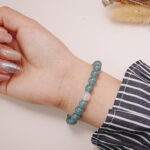 A model wearing the Green Aventurine and Red Agate bracelet on their wrist. The soothing green and vibrant red colors create a balanced, peaceful, and energetic look.