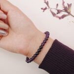 A model wearing the Amethyst and Black Tourmaline bracelet on their wrist. The bold purple and black tones create a striking, yet calming effect, ideal for any occasion.