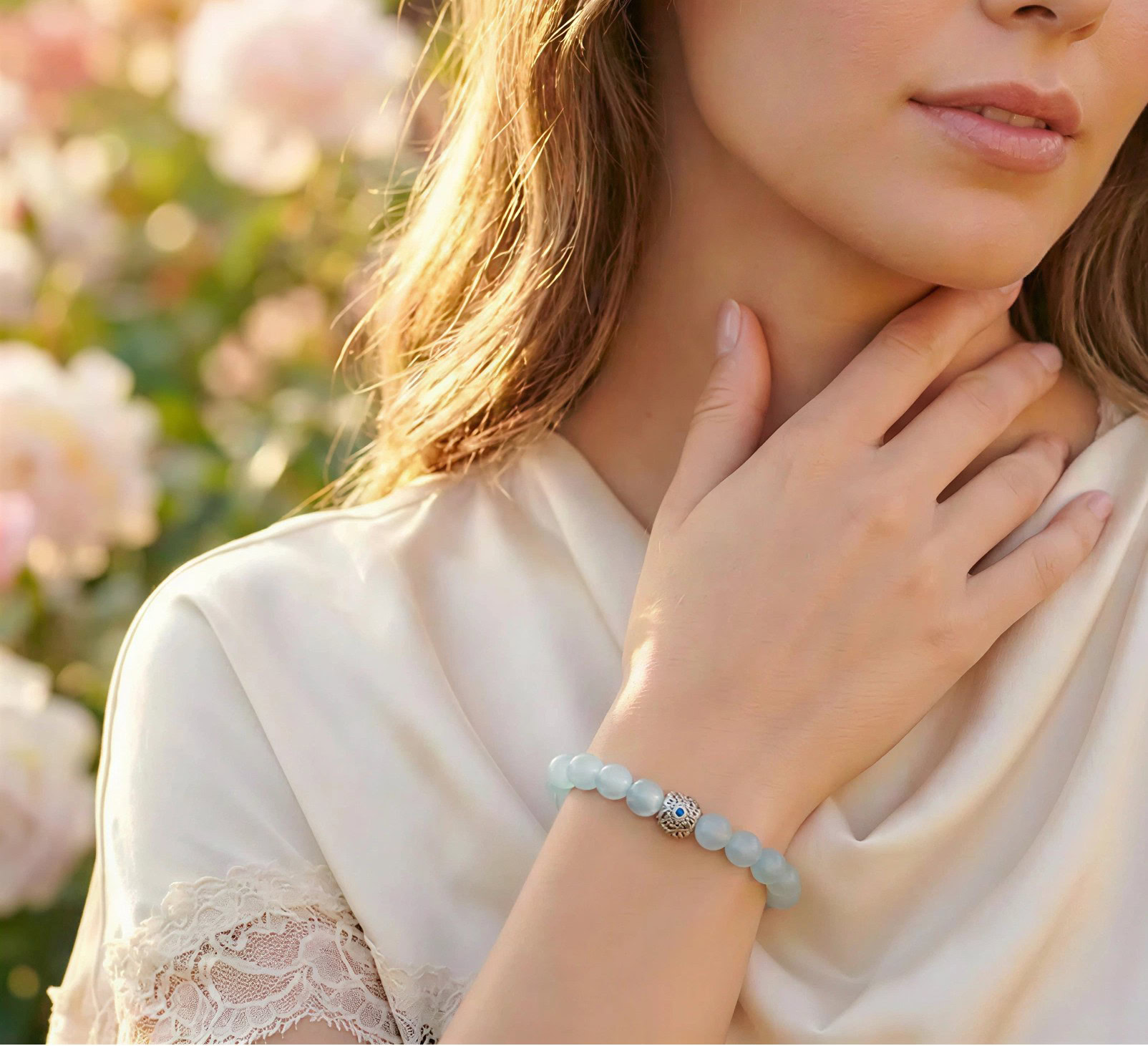 A woman gently touching her neck while wearing a crystal bracelet outdoors, expressing a soft and elegant lifestyle.