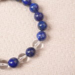 Close-up of lapis lazuli and clear quartz beads, showing smooth surface and deep blue color.