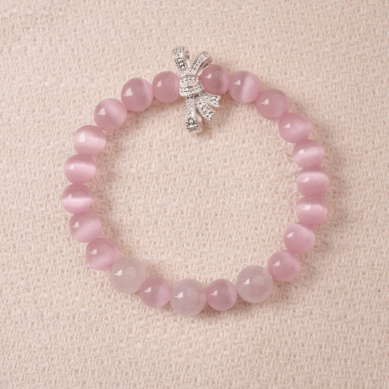Rose quartz bracelet with silver bow charm, symbolizing love, tenderness, and self-care.