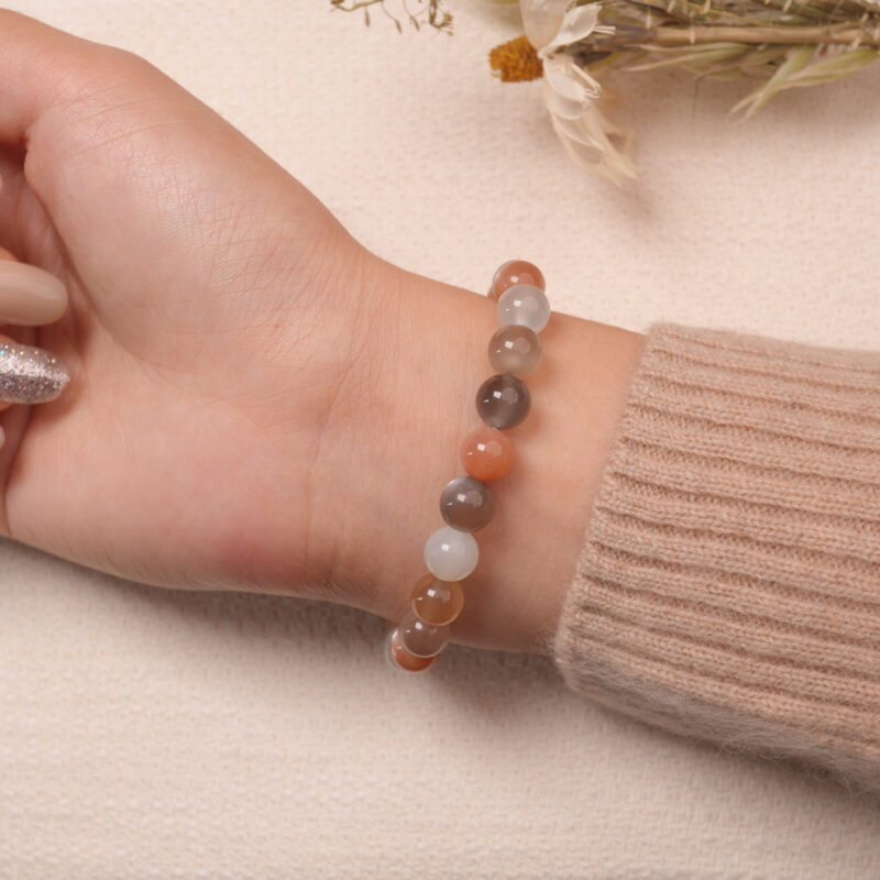 A model wearing the multicolor Moonstone bracelet on their wrist. The soft pastel colors and silver accents create a peaceful and elegant look that complements any outfit.