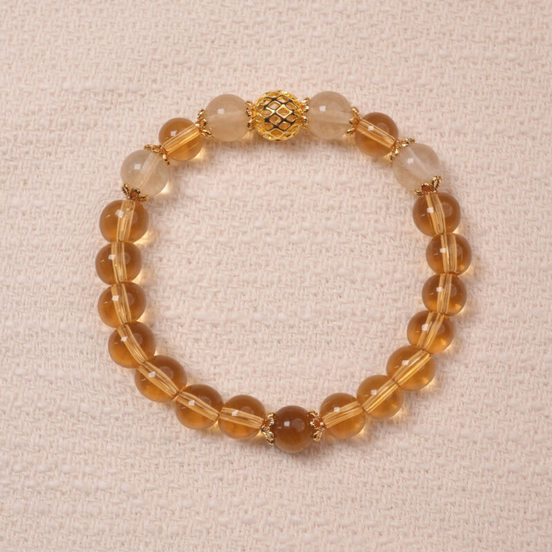 A Citrine bracelet made with smooth, golden Citrine beads. The bracelet features a central golden accent bead, enhancing its luxurious and radiant look.