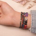 Layered good luck crystal bracelets on wrist, featuring multiple gemstones for positive energy.