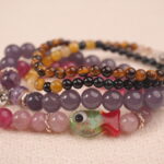Close-up detail of jade and agate bead bracelet stack featuring soft calming colors.