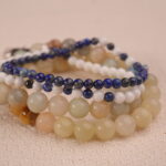 Close-up detail of the calm gemstone bracelet stack, highlighting the bead textures and silver charm.