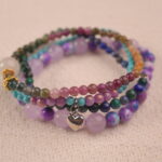Detail close-up of calm gemstone bracelet stack with purple chalcedony, green beads and teal stones