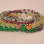 Close-up of multi-gemstone bracelet stack showing varied bead textures symbolizing good luck