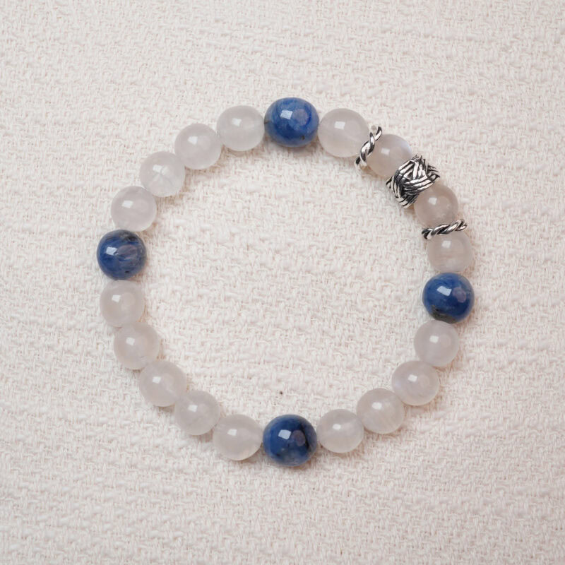 Moonstone and kyanite bracelet photographed under soft daylight on a pink background, highlighting the milky white glow of moonstone and the deep blue tones of kyanite.