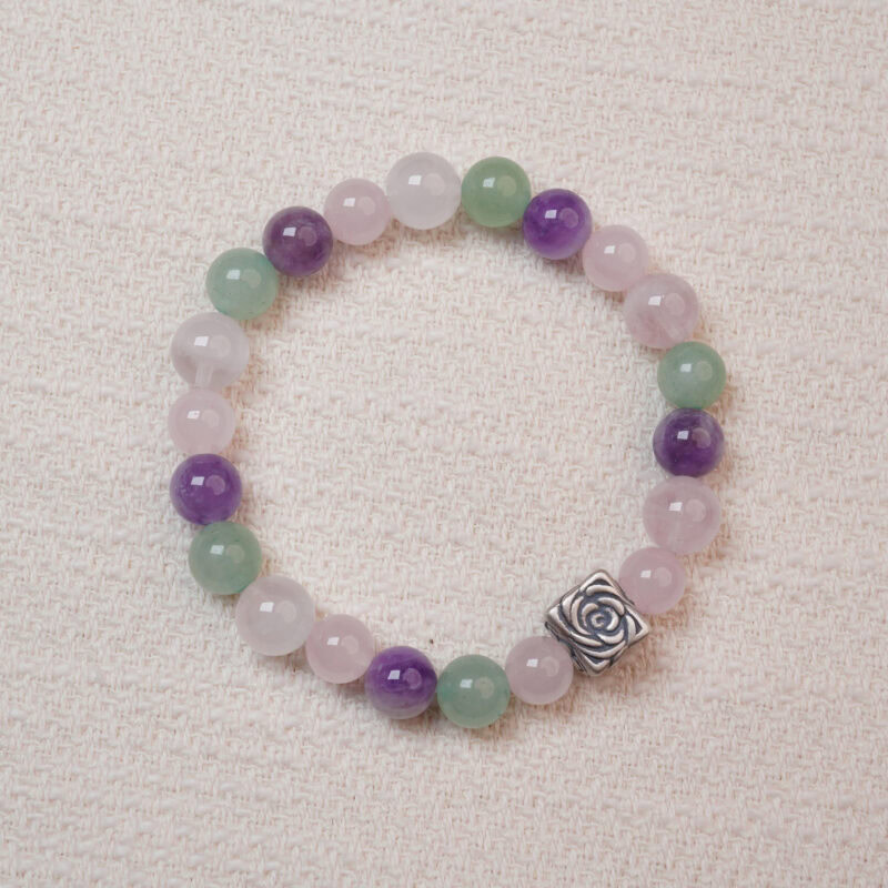 A beaded bracelet made of rose quartz, amethyst, and green aventurine with a silver rose charm.