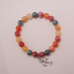 Colorful chalcedony bracelet with a silver heart charm displayed on a soft pink background.